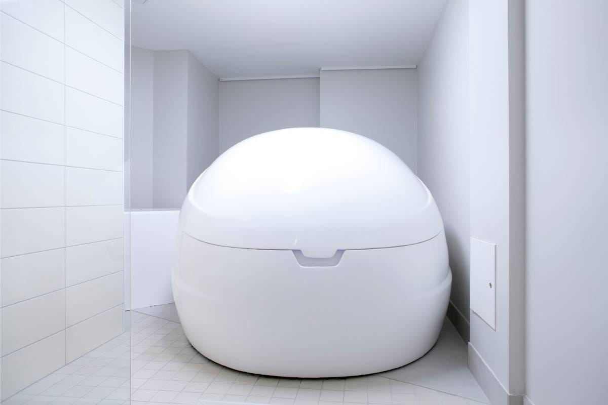 LedSto.fi verkkokaupassa on suuri valkoinen ovaalinmuotoinen aistienvaimennussäiliö, joka sijaitsee minimalistisessa tilassa laatoitettujen seinien ja lattian ympärimänä. Pehmeät LED-valot korostavat säiliön sileää pintaa ja suljettua kantta, tuoden esille sen suunnittelun eristys- tai kelluntaterapiaa varten.